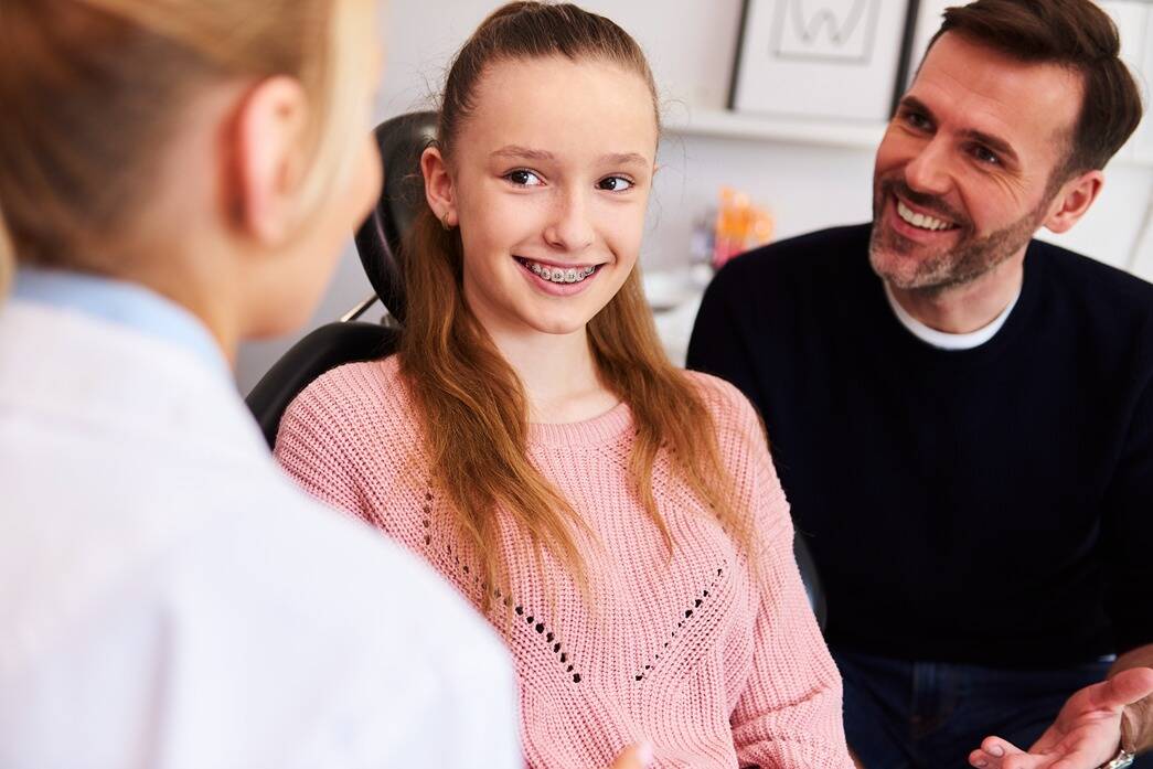 Teen with braces attending an orthodontic consultation with a parent.