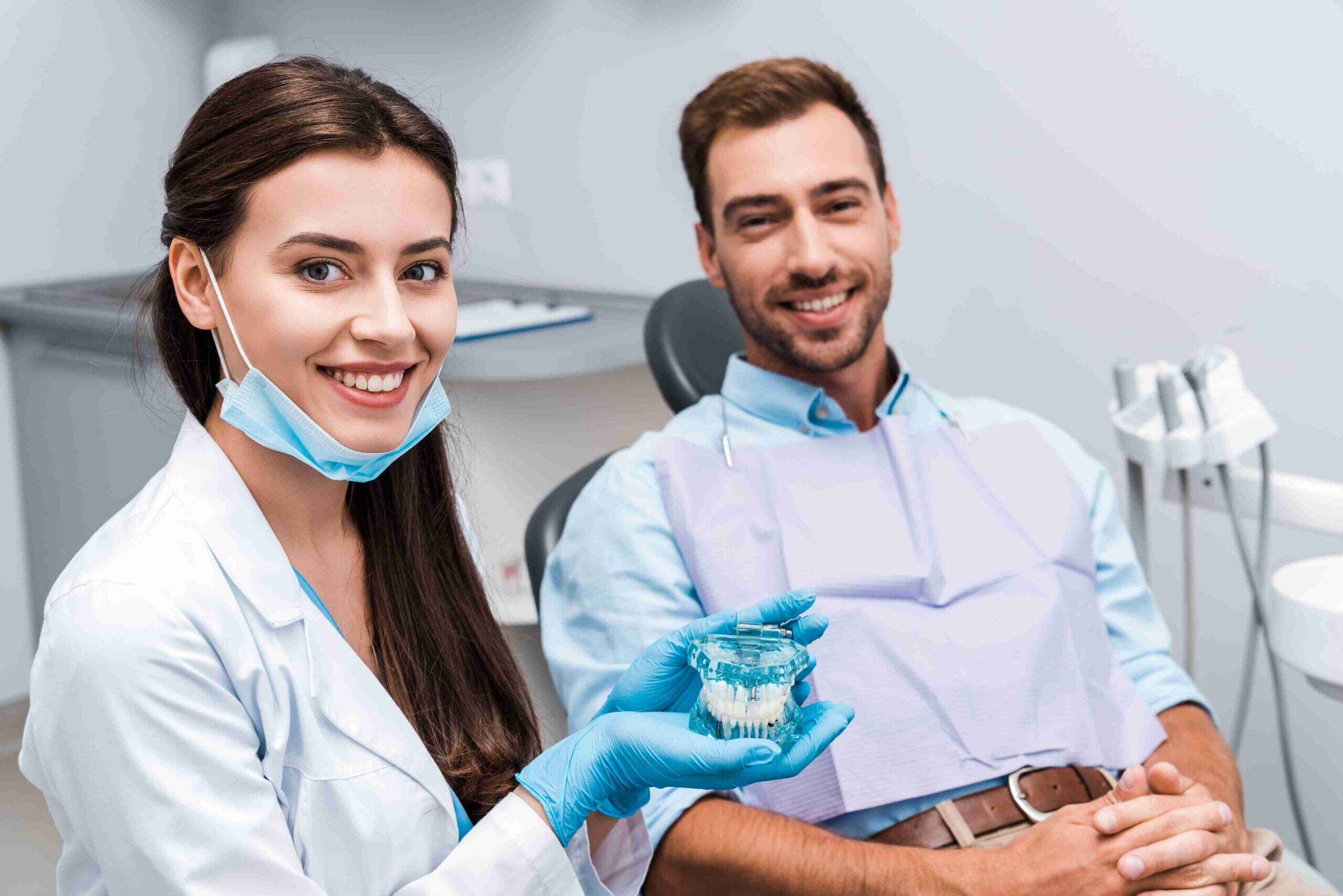 Dentist showing a dental model to a smiling patient.